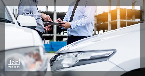 An insurance adjuster asks a client to sign paperwork after a car accident.
